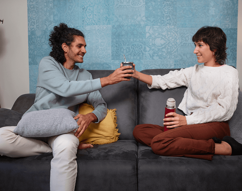 Dos personas compartiendo mate en un sofá, conexión y calidez
